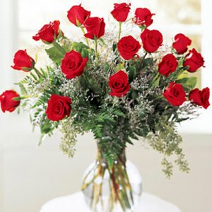 Eighteen gorgeous long stemmed roses elegantly arranged with fresh foliage and accent blossoms in a glass vase. Generally available in red