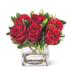 Brighten someone's day with this charming compact bouquet of six or more red roses in a glass cube or vase. A sweet treat that's perfect for a birthday