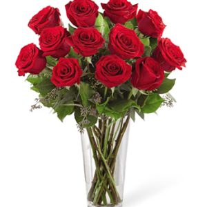 Send a message of love or romance with one dozen premium long-stem red roses arranged with fresh foliage in a tasteful glass vase. Professional florist design and delivery. Popular for love