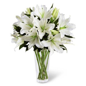 Convey your deepest sympathy and support with the distinctive beauty of pure white lilies designed with fresh foliage in a clear glass vase. Soft
