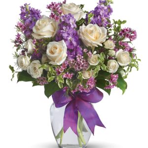 Say it softly with this lovely bouquet of white roses and pretty lavender blooms designed and delivered in a glass vase. Featured flowers include roses