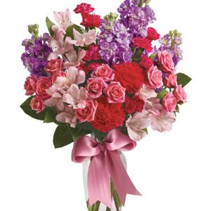 Send smiles across miles with this delightful combination of pretty pink and lavender blooms designed in a slender glass vase and trimmed with a sweet ribbon accent. This popular gift features roses