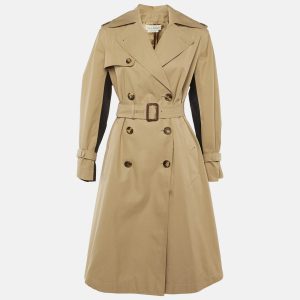 Alexander McQueen’s trench coat in beige cotton blends a classic British silhouette with subtle logo print detailing. Structured shoulders and precise tailoring evoke the label’s dramatic edge. Throw it over monochrome looks to highlight its craftsmanship.