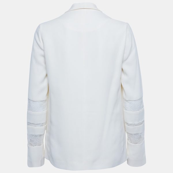 this Maje blazer is designed in cream crepe with delicate lace trim accents. The button front silhouette exudes tailored elegance
